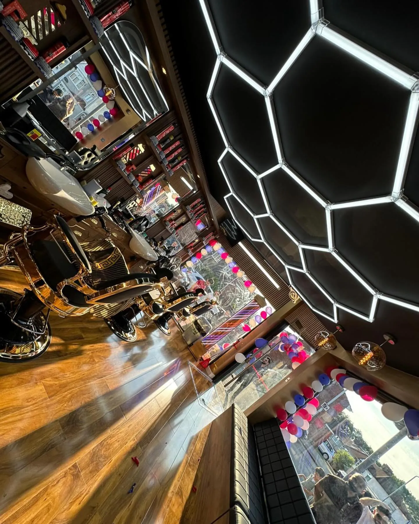 Gold and black barber chairs under the hexagon lights, from a low angle